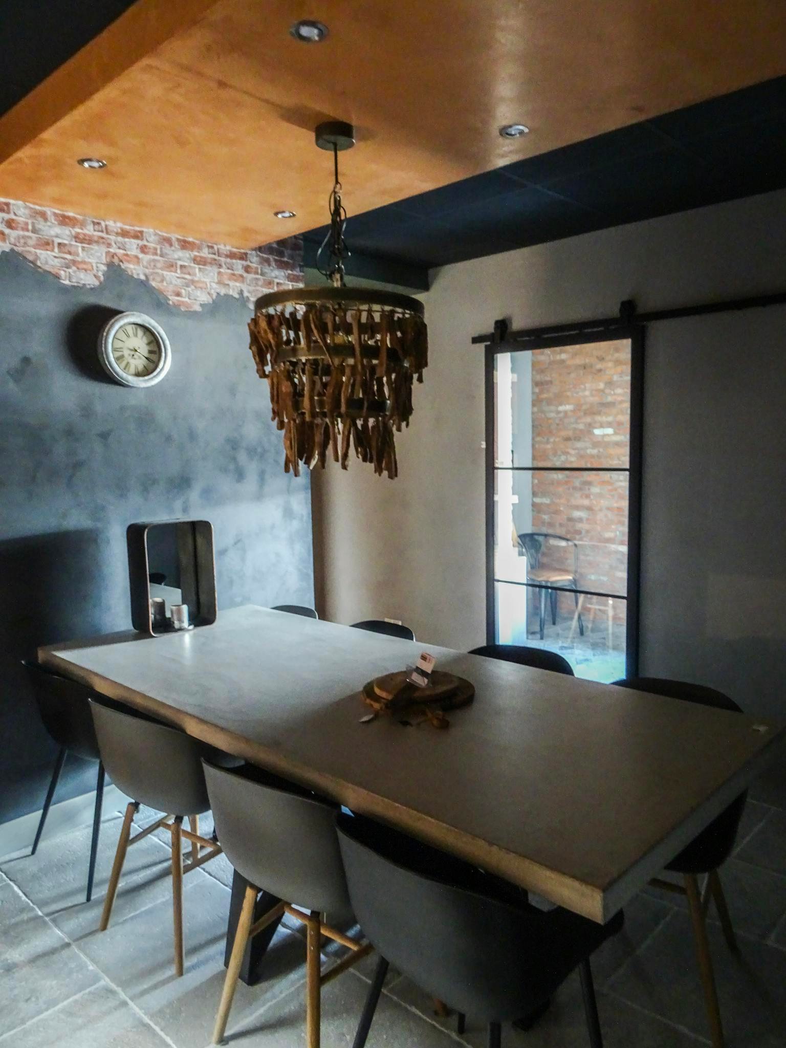 A modern dining room with industrial decor and a rustic chandelier in Sliedrecht.