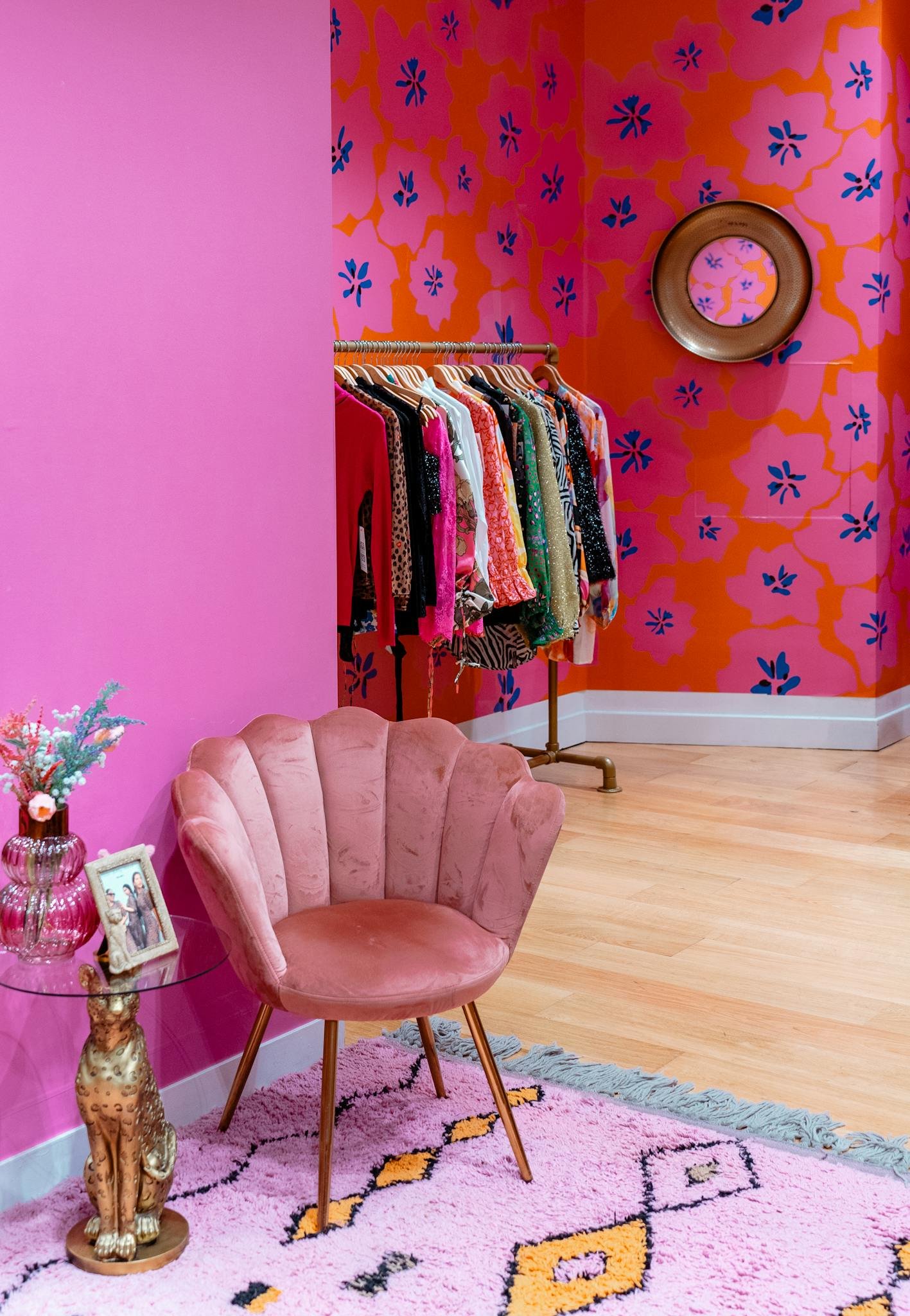 Colorful room with pink armchair and clothing rack creating a chic boutique vibe.